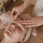 Woman enjoying a soothing facial massage with gua sha tool, promoting relaxation and skin care.