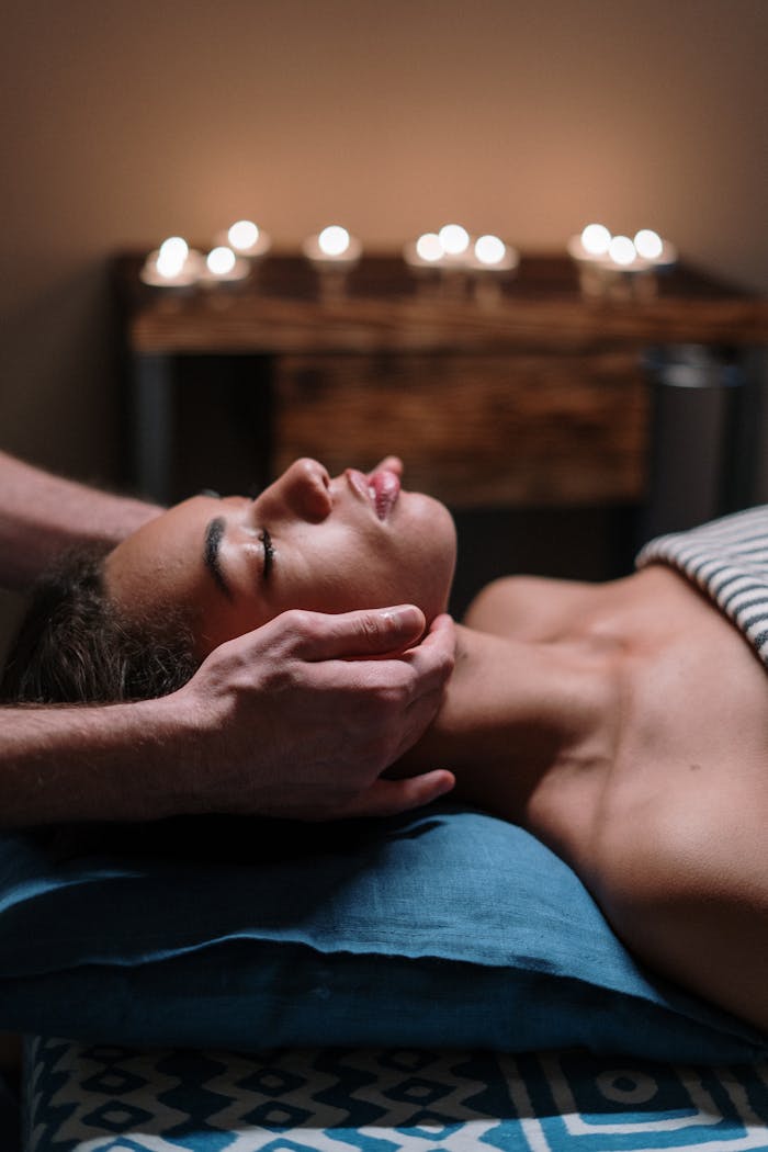 about-03 Woman receiving a calming facial massage in a tranquil spa setting with candlelight.