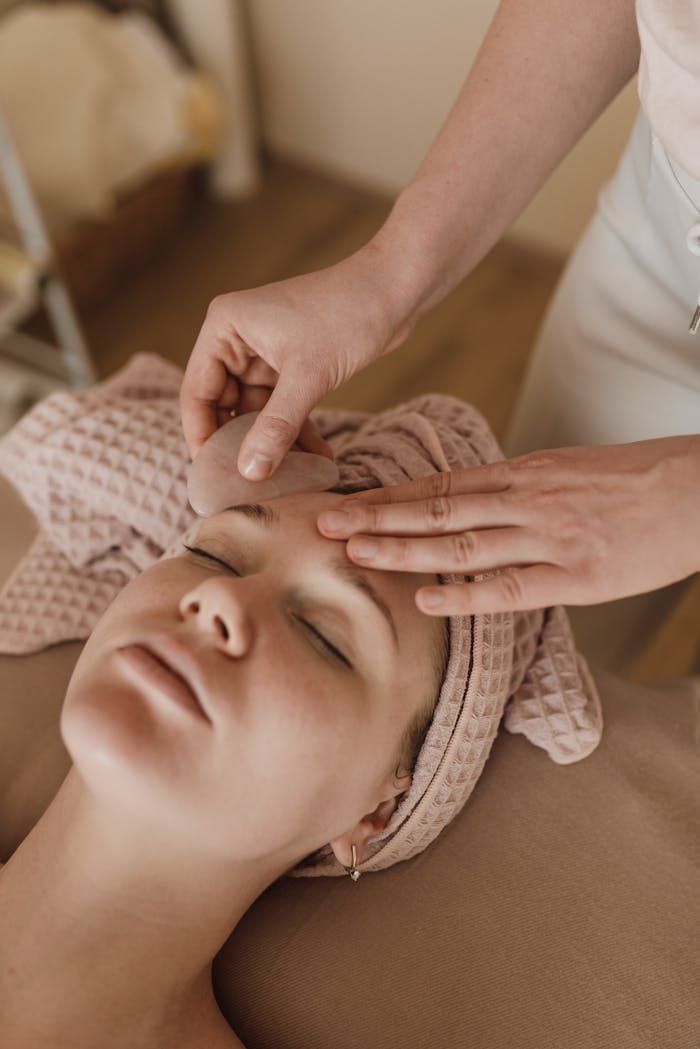 about-02 Woman enjoying a soothing facial massage with gua sha tool, promoting relaxation and skin care.