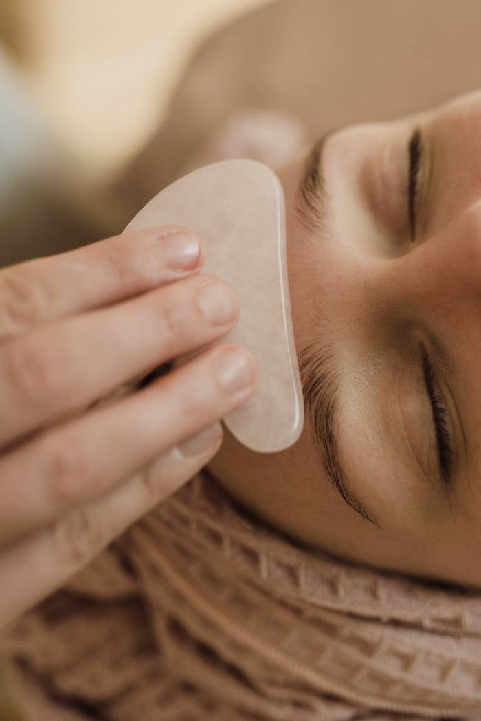 services-01 Close-up of a woman receiving a soothing gua sha facial massage indoors.