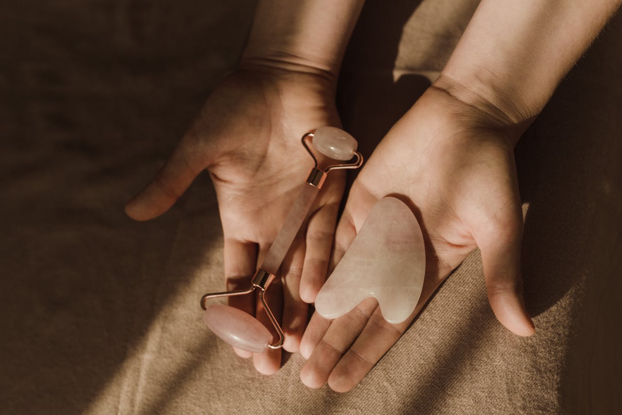 about-01 Close-up of hands holding a face roller and gua sha tool for skincare routine.
